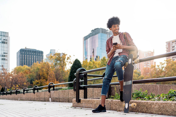 Stock photo of handsome african boy having fun in the city and using his cellphone. - Фото, зображення