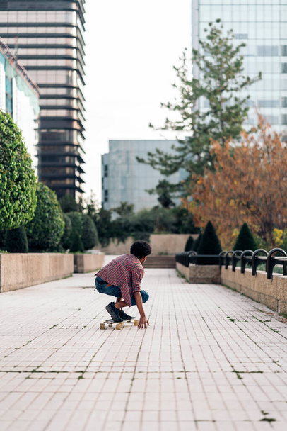 Stock photo of unrecognized afro boy doing skate in the park with his longboard. - Фото, изображение