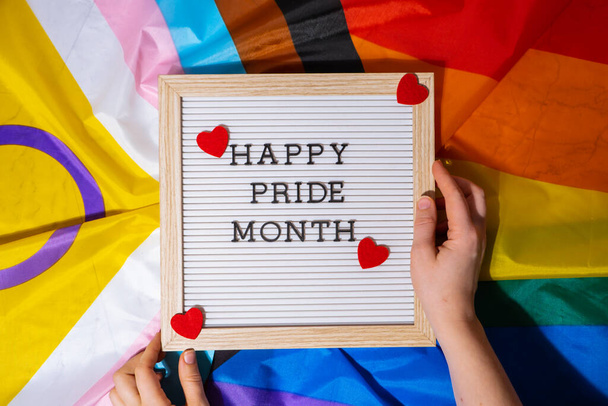 HAPPY PRIDE MONTH frame on Rainbow LGBTQIA flag made from silk material. Symbol of LGBTQ pride month. Equal rights. Peace and freedom. Support LGBTQIA community. Diversity equality - 写真・画像