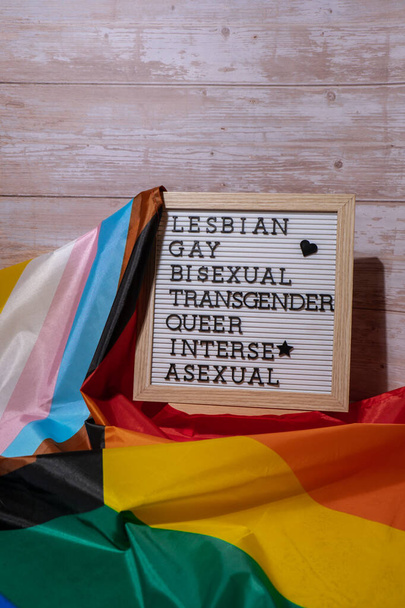 LGBTQIA description frame on Rainbow LGBTQIA flag made from silk material. LESBIAN, GAY, BISEXUAL, TRANSGENDER, QUEER, INTERSEX, ASEXUAL. Symbol of LGBTQ pride month. Equal rights. Peace and freedom - Photo, Image