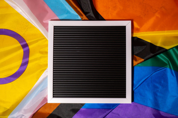 Empty blank frame on Rainbow LGBTQIA flag made from silk material with copy space for your text. Mock up template. Symbol of LGBTQ pride month. Equal rights. Peace and freedom. Support LGBTQIA - Fotoğraf, Görsel