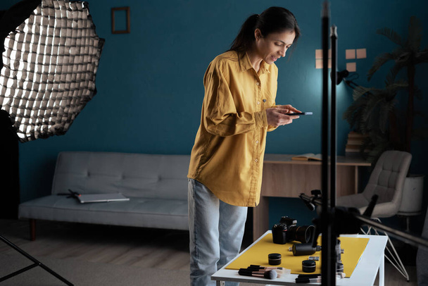 Kobieta fotograf robi zdjęcie produktu urody na smartfonie i aparat cyfrowy w domu studio. Piękno i pielęgnacja ciała treści dla sieci społecznych. Przestrzeń kopiowania - Zdjęcie, obraz