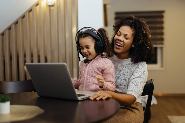 Hymyilevä afrikkalainen amerikkalainen äiti ja tytär käyttävät kannettavaa tietokonetta kotona - Valokuva, kuva