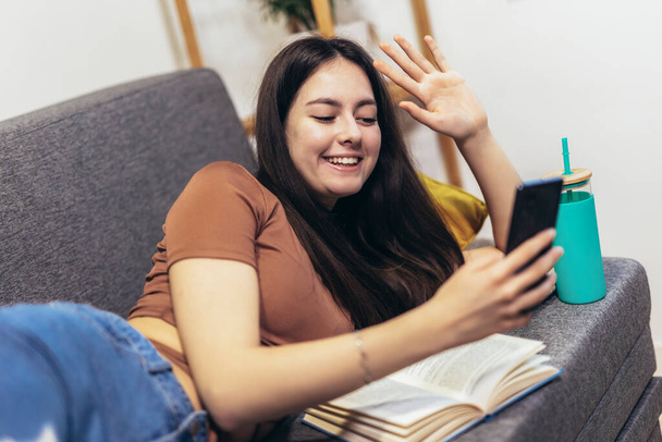 Happy teen girl waving hand using smartphone app enjoying online virtual chat video call with friends - Foto, immagini
