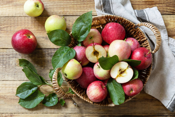 Hintergrund ist die Herbsternte. Bio-Früchte. Bauernmarkt. Korb mit reifen Äpfeln auf einem rustikalen Holztisch. Blick von oben.  - Foto, Bild