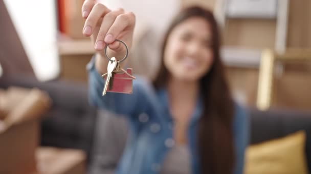 Joven hermosa mujer hispana sonriendo confiada sosteniendo la llave en su nuevo hogar - Metraje, vídeo