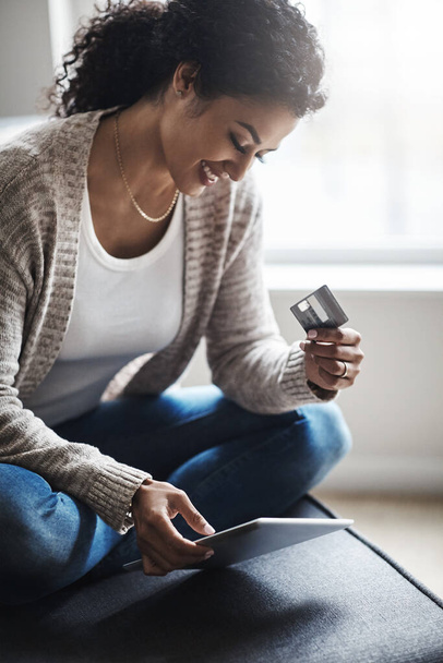 Checking out with a shopping cart full. an attractive young woman using a digital tablet and credit card at home - Photo, Image