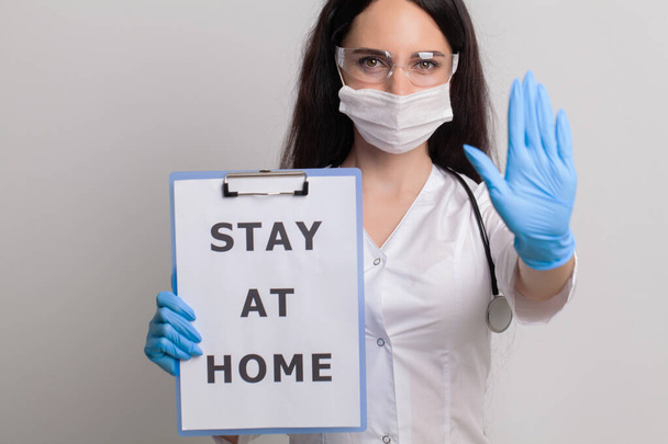 Doctor is holding a sheet of paper with text stay at home. - Photo, Image