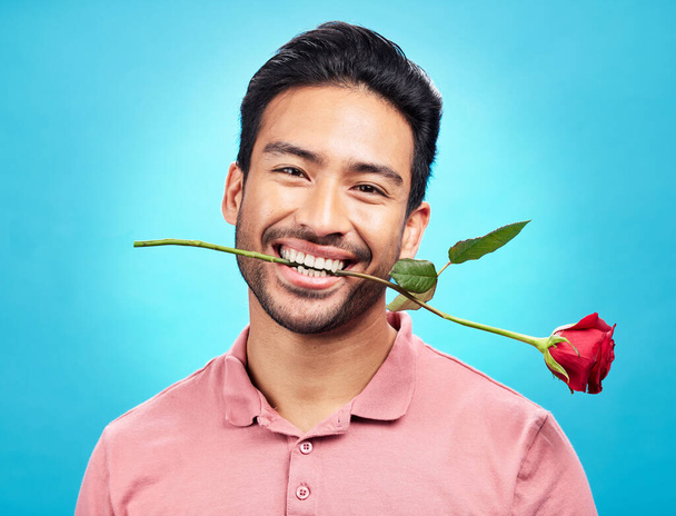 Δόντια, λουλούδι και τριαντάφυλλο με προσωπογραφία του ανθρώπου στο στούντιο για γιορτή, δώρο και ρομαντισμό. Αστεία, ανόητη και παρούσα με αρσενικό απομονωμένο σε μπλε φόντο για την ευτυχία, χαμόγελο και Ημέρα του Αγίου Βαλεντίνου mockup. - Φωτογραφία, εικόνα