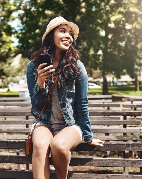 Zeg hallo tegen Summer. een aantrekkelijke jonge vrouw met een mobiele telefoon in het park - Foto, afbeelding