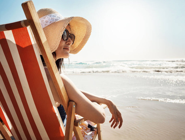 Όλοι χρειαζόμαστε μια offline μέρα τώρα και στη συνέχεια. μια ελκυστική νεαρή γυναίκα που χαλαρώνει στην καρέκλα στην παραλία - Φωτογραφία, εικόνα