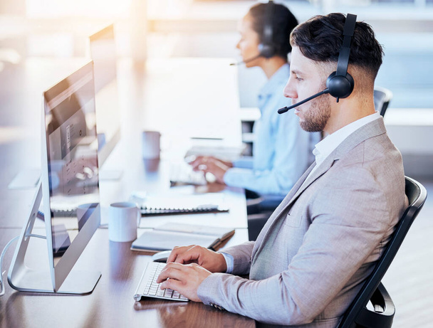 Call center, computer and business with man in office for customer service, technical support or help desk. Telemarketing, contact us or communication for employee and serious operator in tech advice. - Valokuva, kuva