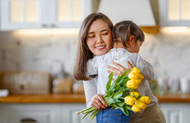 Happy mother's day. Child daughter congratulating her mother and giving her bouquet of flowers. - Valokuva, kuva
