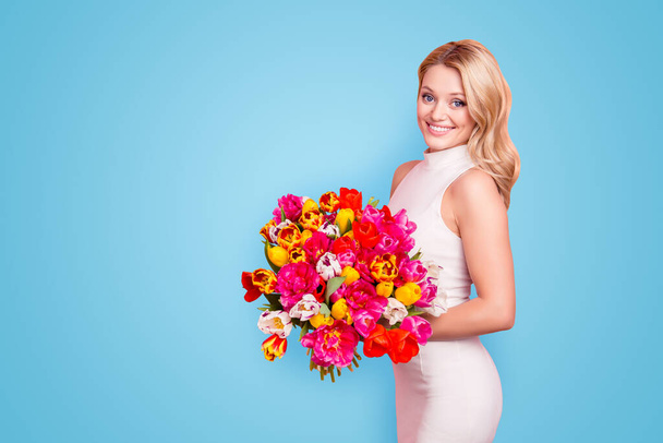 Portrait with copyspace, empty place of lovely elegant charming woman having big bouquet of tulips in hands looking at camera isolated on pink background. - Fotografie, Obrázek