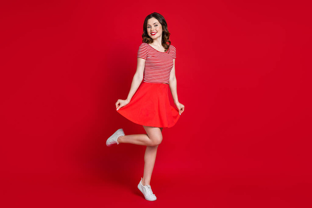 Full body photo of cute girl stand tip toe show new skirt shopping season wear top gumshoes isolated red color background. - Foto, immagini
