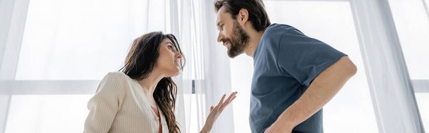 Low angle view of irritated woman talking to boyfriend during conflict at home, banner  - Фото, изображение