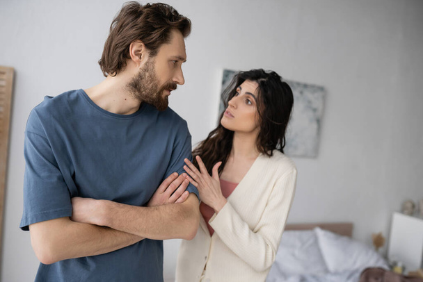 Brunette woman talking to displeased boyfriend during conflict in bedroom  - Fotografie, Obrázek