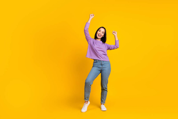 Full size photo of satisfied girl with bob hairdo dressed violet shirt denim pants dancing having fun isolated on yellow color background. - Foto, afbeelding