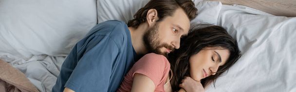 Top view of man looking at sleeping girlfriend on bed at home, banner  - Foto, Bild