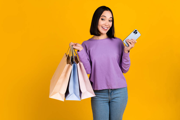 Photo of shiny excited lady dressed purple shirt reading gadget rising bargains empty space isolated yellow color background. - Φωτογραφία, εικόνα