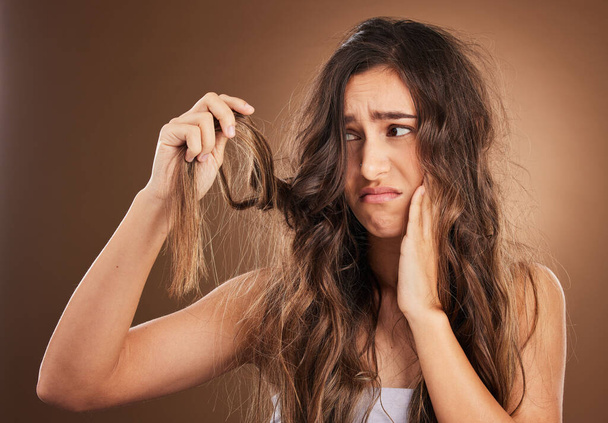 Hair loss, crisis and worried woman in studio for beauty, messy and damage against brown background. Haircare, fail and sad girl frustrated with weak, split ends or alopecia, dandruff and isolated. - Photo, Image