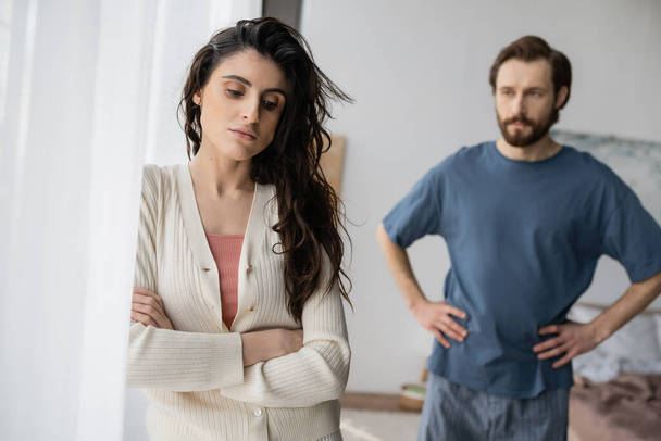 Sad woman standing near blurred boyfriend during relationship difficulties at home  - Photo, Image