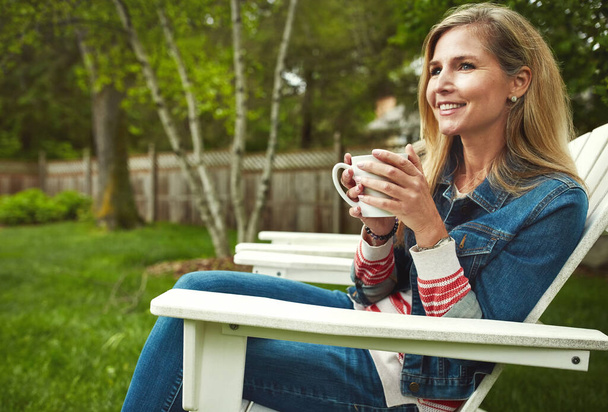 Some coffee and a good view. a mature woman sitting in her backyard - Photo, Image