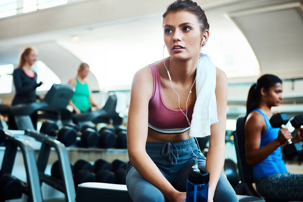 Inspired by the music. an attractive young woman taking a break from her workout in the gym - Fotoğraf, Görsel