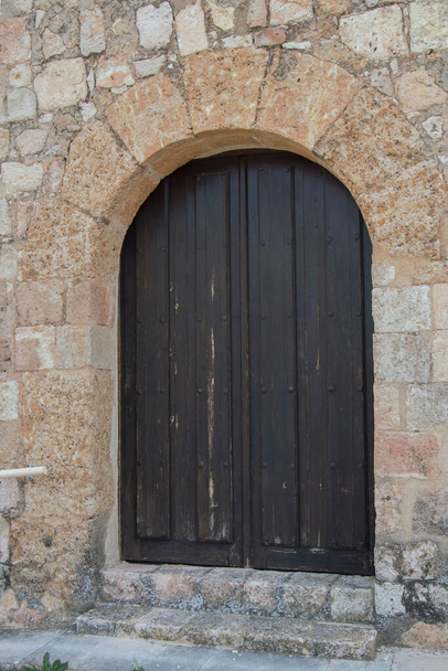 Holztür mit einem halbrunden Bogen in einer Steinfassade  - Foto, Bild