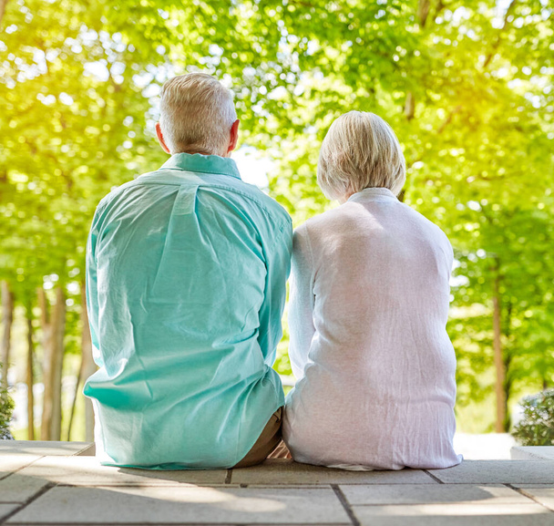 This is the best view. Rearview shot of an affectionate senior couple sitting outside on their porch during the summer - Photo, Image