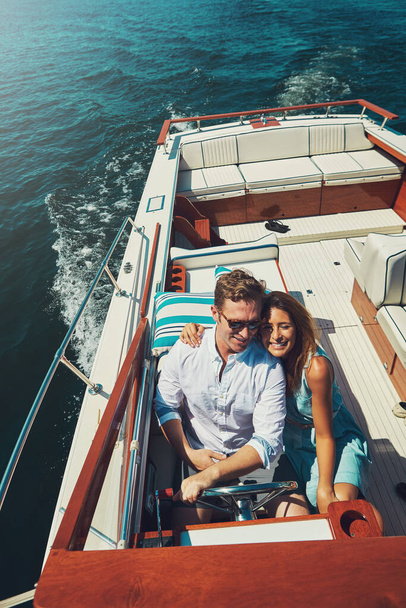 Side by side on the high seas. High angle shot of an affectionate young couple sailing on the open seas in their yacht - Foto, Imagen