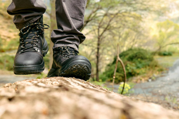 Cestovatel má pěší túru v horském lese. Detailní záběr na lidské nohy v horské botě kráčející po kmeni stromů. Cvičení a fitness v přírodě pro wellness a zdravý životní styl. - Fotografie, Obrázek