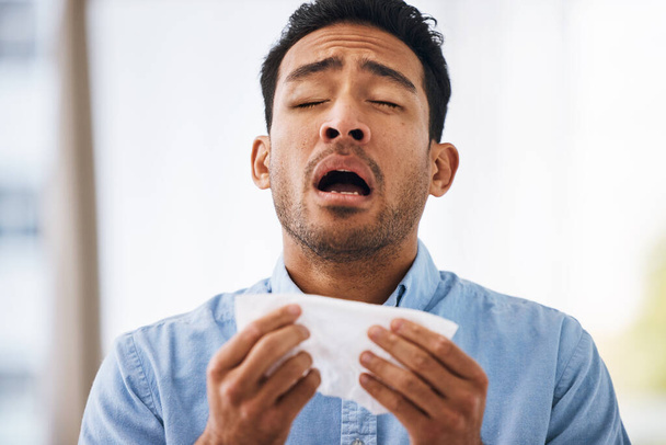 Sick, sneeze and man with a tissue, allergies and sickness with symptoms, cold and illness. Male model, person and guy with congested with sinuses, toilet paper for nose and fever with health issue. - Photo, Image