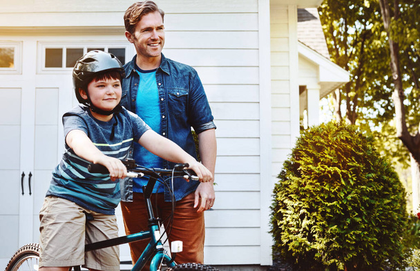 Mit Papas Unterstützung und Ermutigung kann er alles machen. ein Vater bringt seinem Sohn das Fahrradfahren bei - Foto, Bild