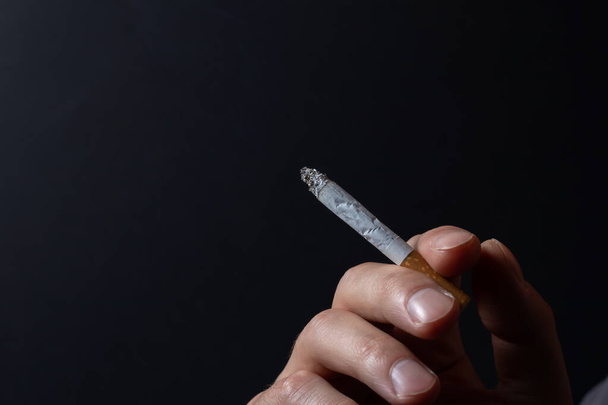 Hand with burning cigarette and smoke on black background. - Fotoğraf, Görsel