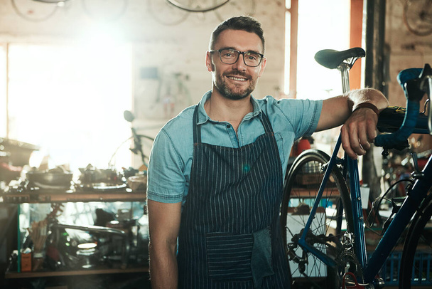 I can repair that. Portrait of a mature man working in a bicycle repair shop - Фото, изображение