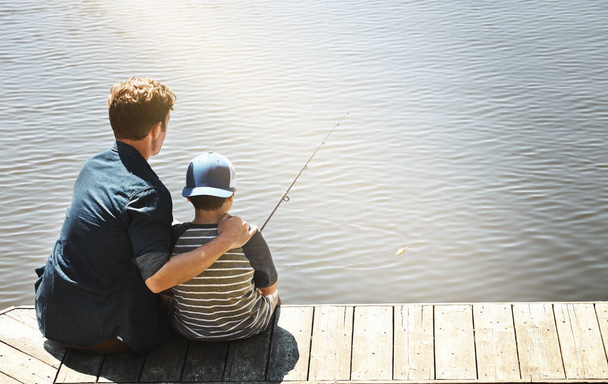 Balıkçılık onların dinlenme yoludur. Bir babanın ve küçük oğlunun birlikte balık tutarken çekilmiş bir fotoğrafı. - Fotoğraf, Görsel
