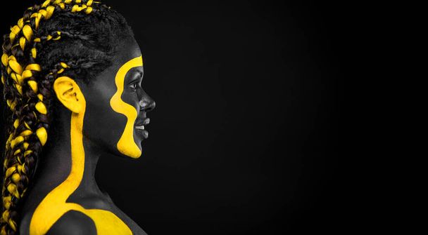 The Art Face. Black and yellow body paint on african woman. Abstract creative portrait. Copy space for your text. - Foto, Imagen