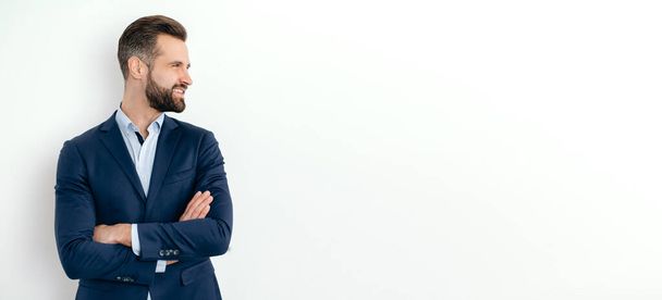 Panoramic photo of positive attractive handsome caucasian successful man in elegant suit, businessman, seo, stand on isolated white background with crossed arms, looking to the side, smile. Copy-space - Foto, Bild