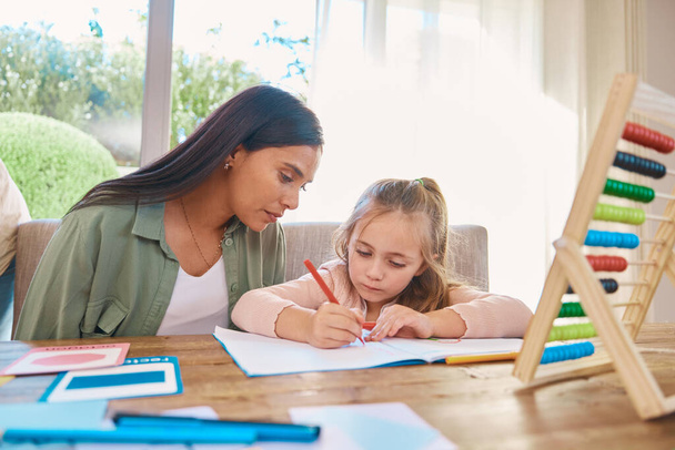 Writing, helping and mother with girl for home school education, language support and creative learning. Math, numbers and family, biracial mom or woman teaching child, drawing and notebook for focus. - Фото, изображение