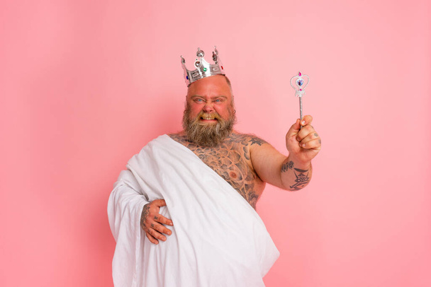 Dikke man gedraagt zich als een koning met een toverstaf - Foto, afbeelding