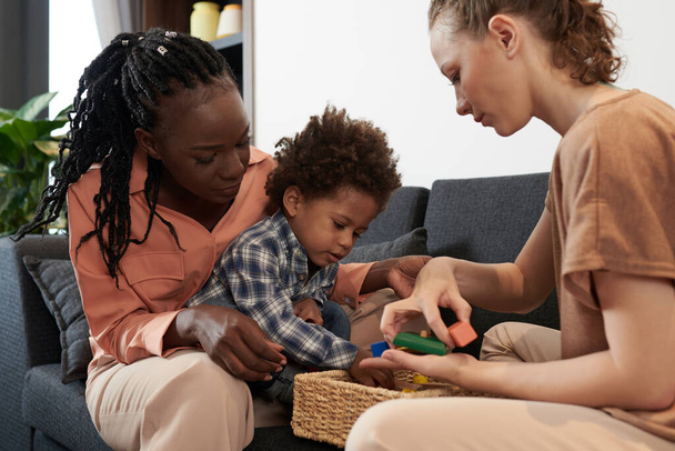 Genitori e piccolo figlio che giocano con blocchi di giocattoli in legno a casa - Foto, immagini