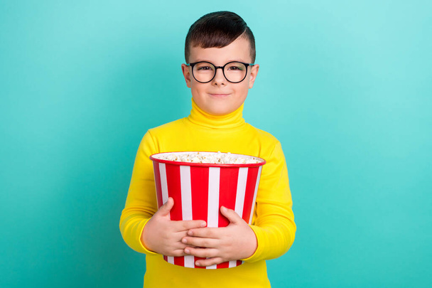 Photo of positive boy hold pop corn bucket enjoying cartoons watching isolated on aquamarine color background. - Фото, зображення