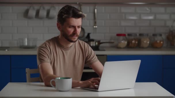 Młody człowiek zrobił sobie kawę i usiadł przy laptopie. Ziewanie człowiek pracuje wcześnie rano, aby zakończyć projekt przed terminem. Wysokiej jakości materiał 4k - Materiał filmowy, wideo