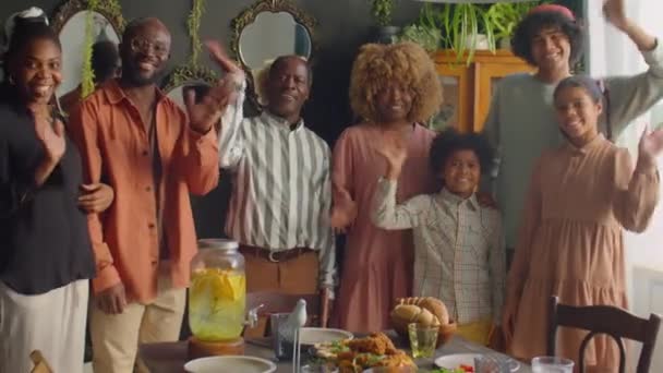 Portrait de groupe de heureuse grande famille afro-américaine souriant et saluant à la caméra tout en posant ensemble à la maison dîner - Séquence, vidéo