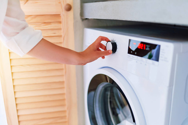 Female hand adjusting and choosing washing mode with button for laundry  - Photo, image