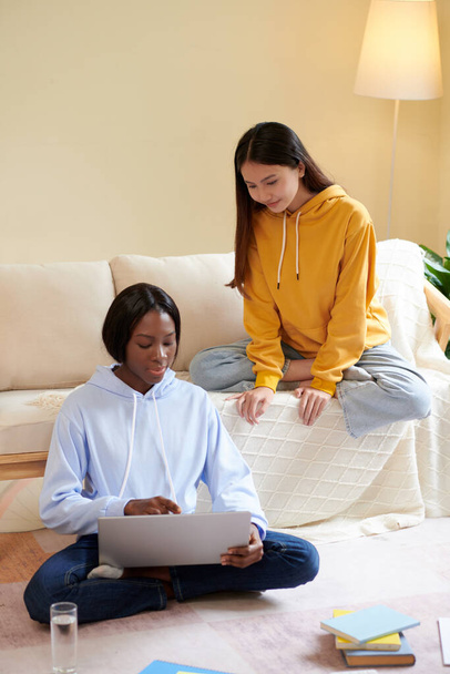 Grave jovem mulher negra mostrando seu código de programação na tela do laptop para amigo e pedindo conselhos - Foto, Imagem