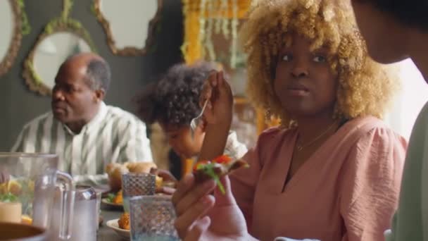 Femme afro-américaine manger le repas et bavarder avec son fils adolescent lors du dîner de vacances en famille à la maison - Séquence, vidéo