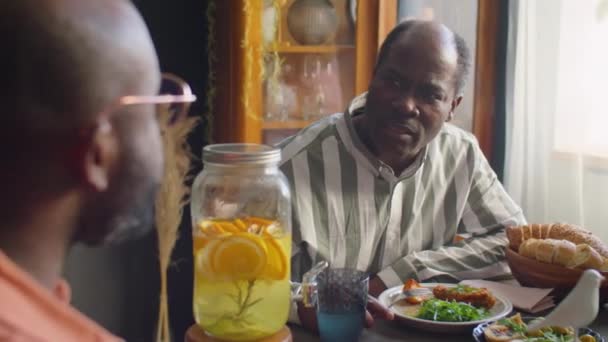 Deux hommes afro-américains mangeant et bavardant au dîner de vacances en famille à la maison - Séquence, vidéo