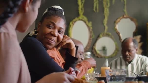 tiro foco seletivo de mulher afro-americana alegre conversando com menina e sorrindo em casa jantar com a família - Filmagem, Vídeo